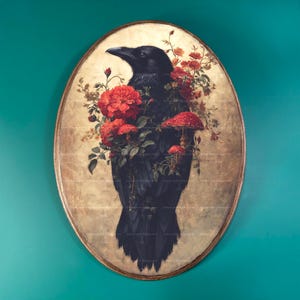 May include: An oval wall art piece featuring a black raven centered against a distressed beige background. The bird is adorned with vibrant red flowers and small red mushrooms with white spots, creating a detailed botanical and avian composition.