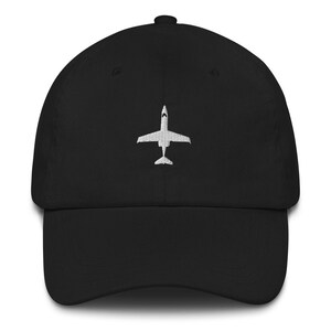 May include: A black baseball cap with a white embroidered airplane design.