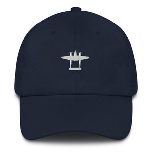 Peut inclure: Une casquette de baseball bleu marine avec une image brodée blanche de trois avions volant en formation.