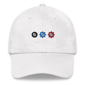 May include: White baseball cap with three embroidered gears, one black, one blue and one red.
