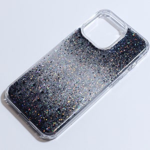 May include: A clear phone case with a black and silver glitter gradient. The glitter is encased in a clear liquid and moves around when the case is tilted.