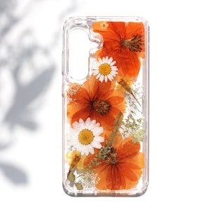 Op de afbeelding: Een transparante telefoonhoes met geperste oranje en witte bloemen. De bloemen zijn verticaal gerangschikt en zijn ingekapseld in hars.