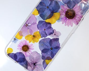 May include: A clear phone case with a pressed flower design. The flowers are purple, yellow, and pink.