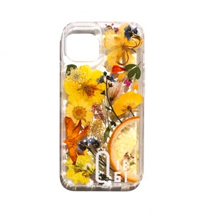 May include: A clear phone case with a pressed flower design. The case features yellow, orange, and white flowers, a slice of dried orange, and a white logo that says "OBI".