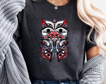 May include: A dark heather grey t-shirt with a colorful graphic of a stylized owl with red, blue, white, and black details. The owl is a traditional Northwest Coast Indigenous art design.