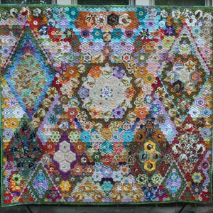 May include: A large, colorful quilt with a complex patchwork design. The quilt features a variety of geometric shapes, including hexagons and diamonds, and is adorned with floral and bird motifs. The color palette includes shades of blue, green, yellow, and purple.
