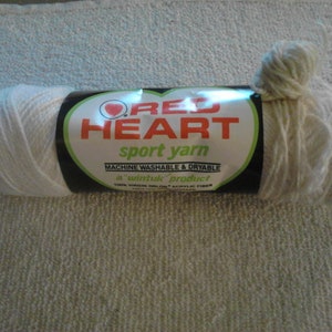 May include: A skein of white Red Heart sport yarn. The label reads "Red Heart sport yarn, machine washable & dryable, a 'win-tuk' product, 100% virgin acrylic fiber."