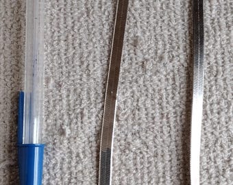 May include: A silver snake chain necklace on a white textured surface. The necklace is about 18 inches long.