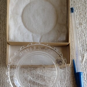 May include: A clear glass plate with a scalloped edge and the words "Writers' Conference" inscribed around the rim. The plate has a raised design of a ship and the words "Ipswich, Fairmont Hotel Company" are printed on the bottom.