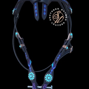 May include: A black leather horse bridle featuring blue and purple braided accents, turquoise-colored floral conchos, and copper-toned hardware. The browband and cheek pieces are decorated with blue diamond-shaped inlays. Includes a metal bit.