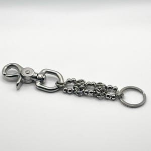 May include: A silver key chain with a swivel clasp, a beaded chain, and a key ring.