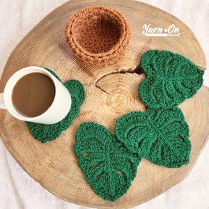 May include: Four green crocheted leaf-shaped coasters with a brown crocheted bowl on a wooden surface. The text "Yarn On" is visible in the top right corner of the image.