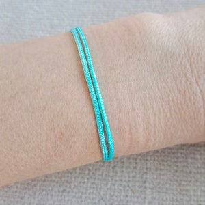 May include: A turquoise blue friendship bracelet made of two strands of cord.