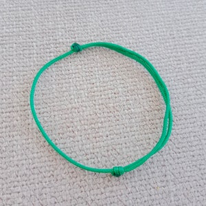 May include: A simple green string bracelet with knots at each end.