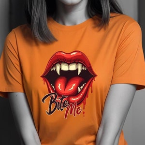 May include: Orange t-shirt with a graphic of a red, open mouth with fangs and a tongue sticking out. The text "Bite Me" is printed below the mouth.