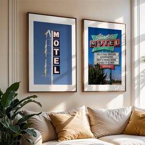 May include: Two framed prints of vintage motel signs hang above a beige sofa with gold pillows. One print shows a blue sky with the word "MOTEL" in neon lights. The other print displays a sign that reads "Starlite MOTEL" with additional text.