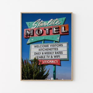 May include: A framed print of the Starlite Motel sign against a blue sky. The sign features the word "MOTEL" in large, chrome letters, with "Starlite" in cursive above. Additional text includes "Welcome Visitors," "Kitchenettes," and "Vacancy."