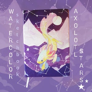 May include: Watercolor sketchbook featuring a whimsical axolotl design against a purple night sky with mountains and constellations. The cover art includes the words "Watercolor" and "Axolotl Stars". A white ribbon bookmark is visible.
