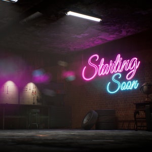 Może przedstawiać: Słabo oświetlony pokój z ceglanymi ścianami i neonowym szyldem z napisem "Starting Soon". Szyld jest różowy i niebieski. W pokoju znajdują się beczki i stół z krzesłem.