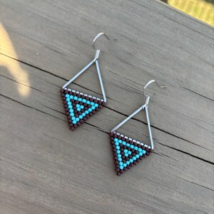 May include: A pair of silver triangle earrings with brown and turquoise beaded designs.
