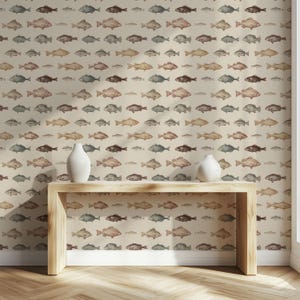 May include: Wallpaper featuring a repeating pattern of watercolor fish in shades of brown, tan, and blue on a cream background. Two white ceramic vases sit on a wooden console table. The wallpaper covers the wall.