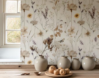 May include: A neutral-toned interior scene featuring a wooden table with a selection of decorative items. The table holds a wooden plate with apples, small ceramic bowls, and a collection of beige vases. The backdrop is a floral wallpaper with a window.
