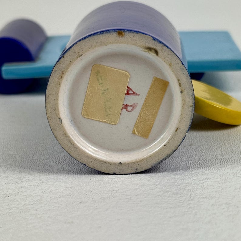 May include: The bottom of a blue ceramic cup with a white sticker that says "A.R.  Kitzingen Germany".