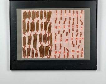May include: A framed artwork with a grid pattern and numbered squares. The squares are filled with small, brown, rectangular pieces of paper. The numbers 1 through 28 are written in red on the grid.