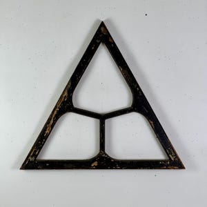 May include: A triangular wooden frame with a distressed black finish, featuring three internal sections separated by a central Y-shaped divider. The wood shows visible wear and chipped paint, revealing a lighter brown tone underneath the black surface.