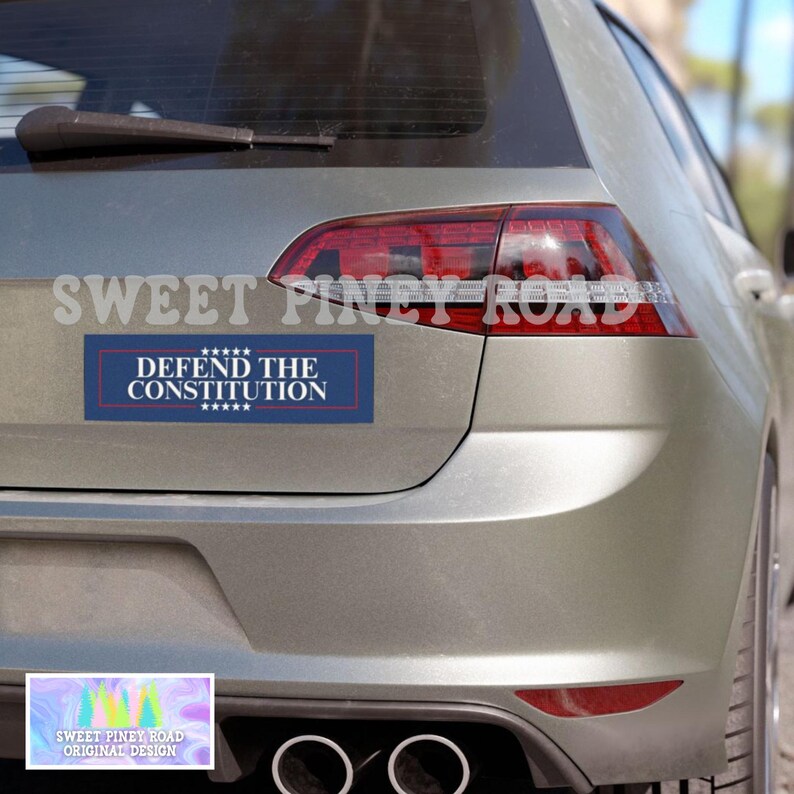 Puede incluir: Un coche plateado con una pegatina de parachoques azul y blanca que dice "DEFEND THE CONSTITUTION" con estrellas arriba y abajo del texto. La pegatina est&aacute; en la parte trasera del coche, debajo de los faros traseros.