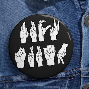 May include: Black and white button with the word "LOVE" spelled out in American Sign Language.