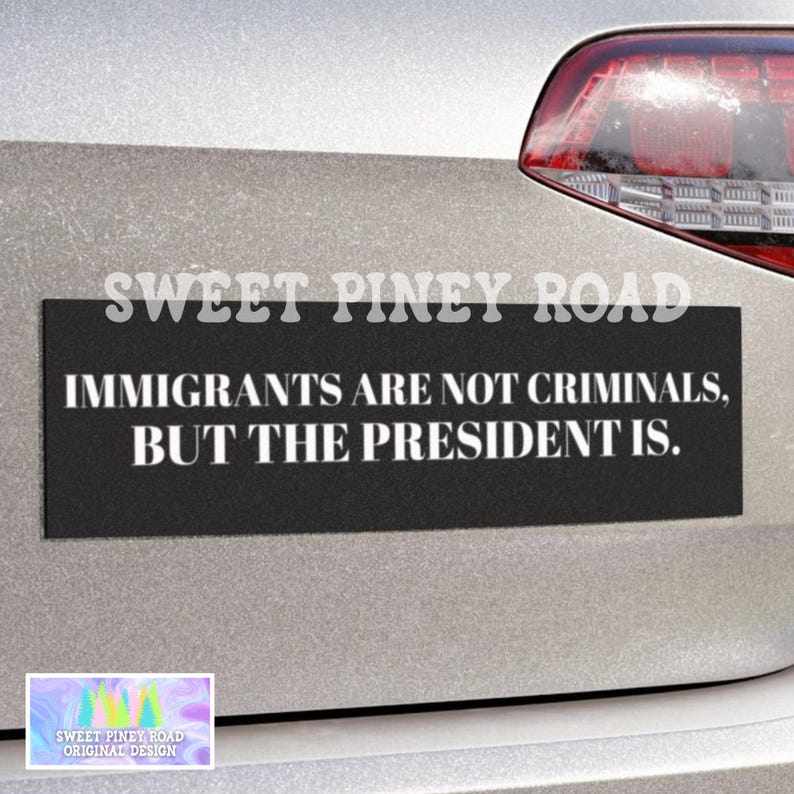 May include: A black rectangular bumper sticker with white text that reads "IMMIGRANTS ARE NOT CRIMINALS, BUT THE PRESIDENT IS." The sticker is affixed to a silver car. The text "SWEET PINEY ROAD" is above the text.
