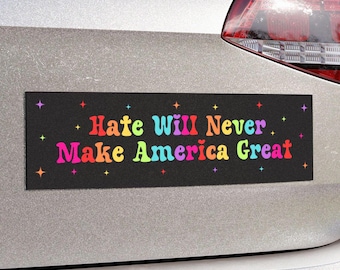 以下が含まれることがあります： 虹色の文字で「Hate Will Never Make America Great」と書かれた黒いバンパーステッカー。ステッカーには、背景に小さな白い星が散りばめられています。