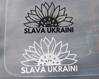 Może przedstawiać: Dwa czarne i białe naklejki z słonecznikiem z tekstem "SLAVA UKRAINI" na szybie samochodu.
