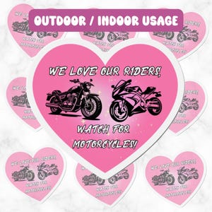Puede incluir: Pegatinas en forma de corazón rosa con el texto "We love our riders! Watch for motorcycles!" e imágenes de dos motocicletas. Las pegatinas están diseñadas para uso en exteriores o interiores.