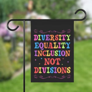 May include: A black garden flag with the words "Diversity Equality Inclusion Not Divisions" in rainbow colors.