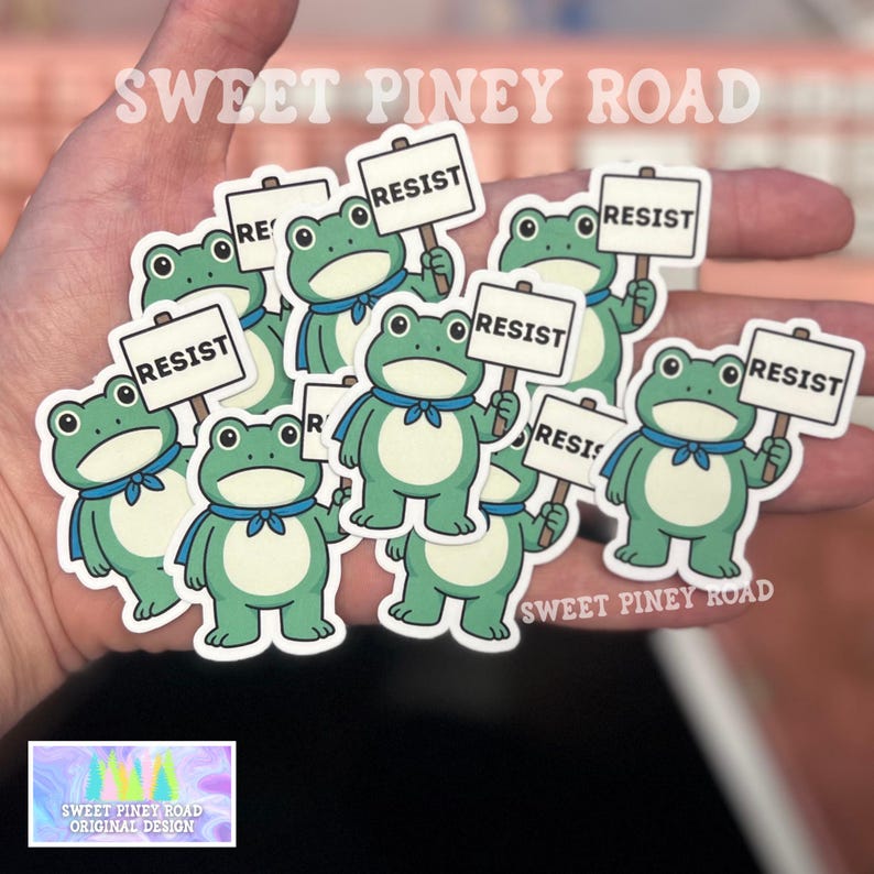 Puede incluir: Una colecci&oacute;n de pegatinas con una rana de dibujos animados sosteniendo un cartel que dice "RESIST". Las ranas son verdes y blancas con pajaritas azules. Tambi&eacute;n se ve el texto "SWEET PINEY ROAD" y "ORIGINAL DESIGN".