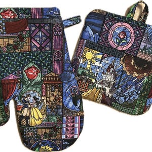 May include: A set of two kitchen pot holders featuring a stained glass design inspired by the Disney movie Beauty and the Beast. The design includes a castle, roses, and other elements from the movie.