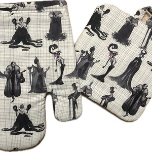May include: Oven mitt and pot holder set with a black and white villain print. The set features a repeating pattern of various villain characters on a light beige background with a grid pattern. The oven mitt has a loop for hanging.