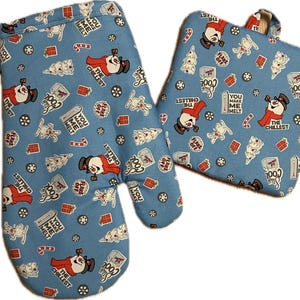 May include: A set of two blue oven mitts with a snowman pattern. The mitts feature the text "You Make Me Melt" and "The Chillest" repeated throughout the pattern.