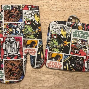 May include: A Star Wars-themed oven mitt and pot holder set. The set features a comic book style design with characters like Chewbacca, R2-D2, and Boba Fett. The words "STAR WARS" are printed on the pot holder.
