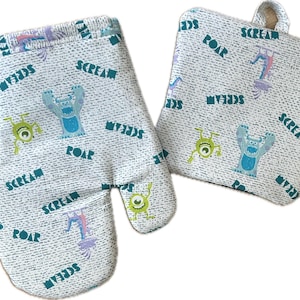 May include: A set of two white oven mitts with a blue and green monster print. The mitts feature the words "Scream", "Roar", and "My Buds" repeated throughout the print.