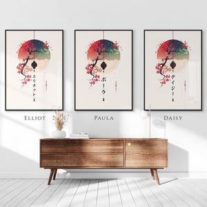 May include: Three framed art prints with Japanese-inspired designs. Each print features a stylized tree with cherry blossoms, a red and blue circular background, and Japanese text. The prints are labeled "Elliot", "Paula", and "Daisy".