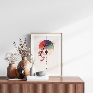 May include: A framed art print featuring a Japanese-inspired design with a red and blue circular motif, a tree branch, and Japanese characters. The print is displayed on a wooden cabinet, alongside vases and decorative items.
