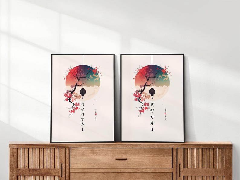 May include: Two framed art prints featuring a Japanese-inspired design. Each print showcases a colorful circular background with a tree branch, lantern, and Japanese text. The prints are displayed on a wooden cabinet.