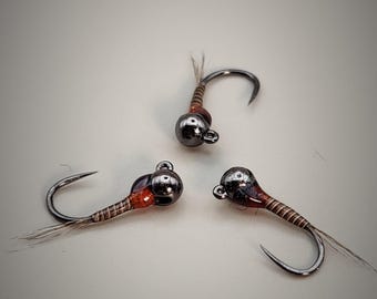 May include: Three small, brown and black fly fishing lures with a bead head.