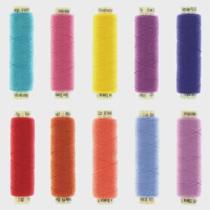 May include: A collection of ten spools of thread in various colors, including teal, pink, yellow, purple, and blue. Each spool is labeled with text indicating the thread type and color. The threads are arranged vertically against a light background.