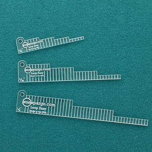May include: Three clear plastic rulers with a graduated scale and the text "suespargo.com Loop Easy Made in the USA" printed on each ruler.