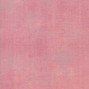 May include: A solid pink fabric with a textured appearance. The color is a soft, muted pink, with subtle variations in tone across the surface. The fabric has a slightly distressed or aged look, with visible texture.