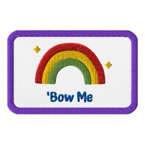 May include: Embroidered patch featuring a rainbow design in red, yellow, and green, with two yellow star accents. The patch has a white background and a purple border. The text "Bow Me" is embroidered in blue.